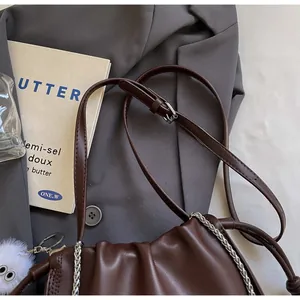 Detail view of brown pleated cloud bag with leather strap and silver chain link