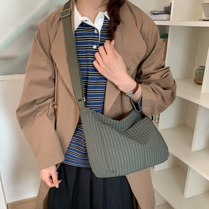 Detail view of dark green checkered crossbody bag featuring adjustable wide shoulder strap