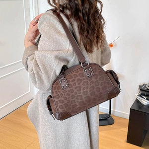 Détail du sac à bandoulière léopard marron avec rivets argentés porté par le mannequin