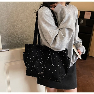 Detail view of large star-print canvas tote bag featuring side pockets and a handmade logo