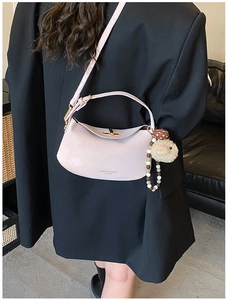 Detail of pink leather half-moon shoulder bag with plush sheep charm and beaded chain