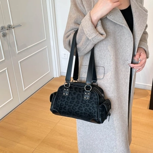 Sac Boston vintage imprimé léopard avec rivets argentés et anneaux porté par un mannequin