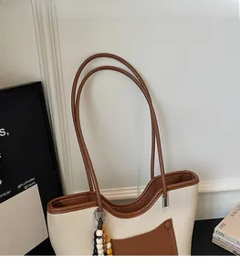 Detail view of the bicolor tote bag showing cream lychee grain leather and brown strap
