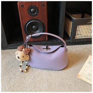 Detail of light purple leather handbag with silver clasp and cute plush bear charm