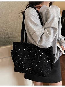 Minimalist black canvas tote bag with star patterns and drawstring closure worn by model