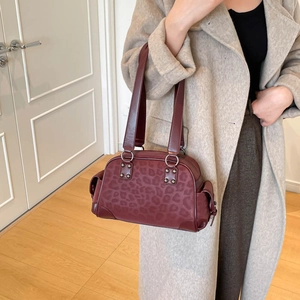 Détail d'un sac sous le bras léopard bordeaux avec rivets vintage et anneaux en métal