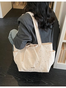 Minimalist beige canvas tote bag with star print and bow detail on model in library