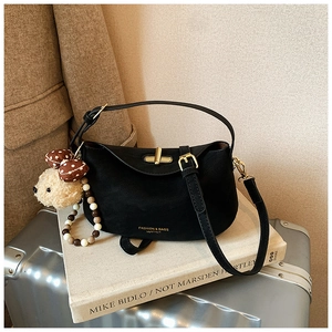 Detail of black leather saddle bag with gold metal clasp and plush bear charm decoration