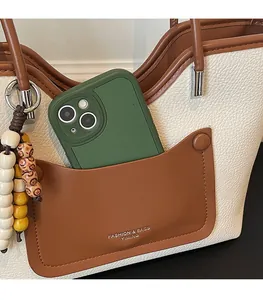 Close-up of front pocket on cream and brown tote bag showing phone storage detail