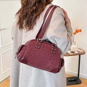 Détail du sac à bandoulière bordeaux avec motif léopard et rivets métalliques
