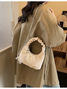 Beige crescent bag with pleated handle, pearl bow pendant and metal chain strap