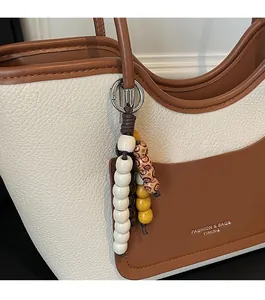 Detail of lychee pattern leather tote bag with contrast pocket and beaded charm