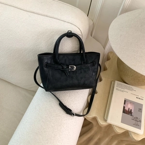 Minimalist black tote bag in matte leather with silver buckle and adjustable shoulder strap