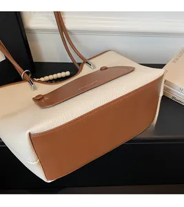 Detail view of contrast color tote bag showing cream lychee grain leather and brown strap