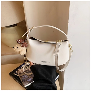 Detailed shot of white leather shoulder bag with cute bear charm and golden buckle