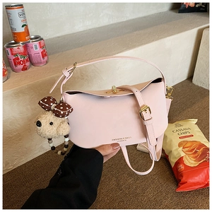 Detail of light pink leather handbag featuring gold metal twist lock and cute puppy charm