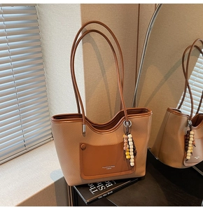 Detail of pebbled leather tote bag with contrast pocket and colorful ethnic charm
