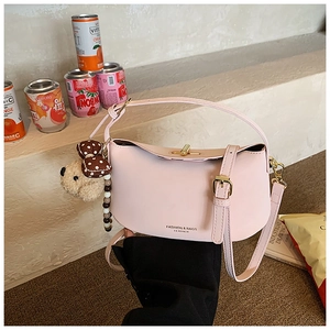 Close-up of pink fashion bag with gold twist lock and cute teddy bear charm