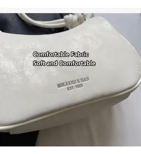 Detail of white dumpling bag with metallic logo and textured synthetic leather