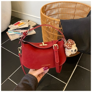 Detail of red leather handbag with gold logo, turn-lock closure and dog charm accessory