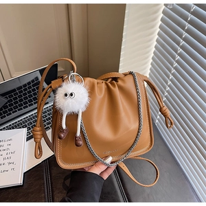 Detail of brown pleated cloud crossbody bag with silver chain and plush monster charm
