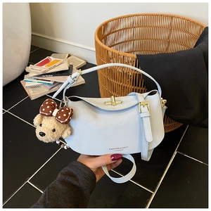 Detail of light blue crossbody bag with gold twist lock and cute plush bear charm