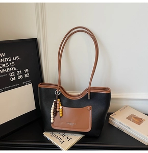 Detail of color-block tote bag with litchi grain leather and beaded tassel charm