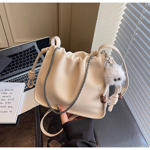 Detail of beige ruched cloud bag with chain strap and cute fuzzy pompom accessory