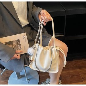 Detail of off-white cloud bag with metal chain and plush doll pendant in a street style
