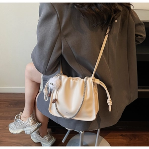 Detail view of off-white pleated cloud bag with silver chain and plush ball accessory