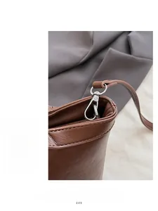 Detailed macro shot of silver metal buckle and brown pebble leather texture on tote bag