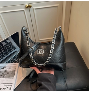 Detail van zwarte gewatteerde hobo-tas met zilveren kettinghandvat en metalen logo