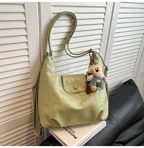Detail view of sage green lychee faux leather tote bag with a cute plush bear charm