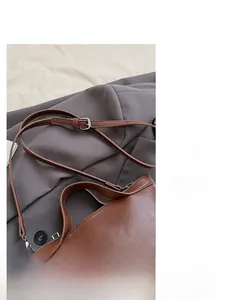 Detail of adjustable leather shoulder strap with silver metal buckle on brown tote bag