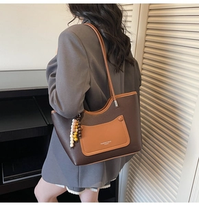 Detailed view of deep brown pebbled leather tote bag with stylish wooden bead accessory
