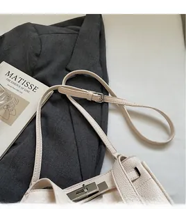 Close-up of beige lychee grain leather shoulder bag with silver metal swivel lock