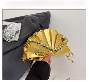 Detail of golden shell-shaped evening clutch bag with beaded handle and chain strap