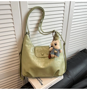Detail of light green PU leather shoulder bag with cute brown teddy bear keychain