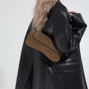 Detail view of brown suede baguette bag with silver studs and adjustable shoulder strap
