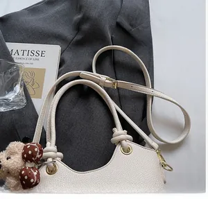 Detail van witte handtas met lychee-patroon, berenhanger en gouden metalen oogjes