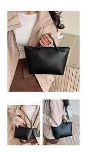 Detail view of black minimalist leather tote bag showing crossbody and handheld modes