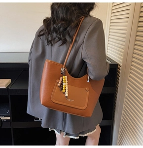Brown litchi grain tote bag detail featuring colorful beaded charm and front pocket