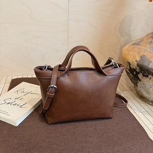 Detailed view of brown matte leather tote bag with dual handles and adjustable strap
