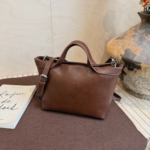 Detail of dark brown faux leather tote bag with silver hardware on a cozy knit cushion