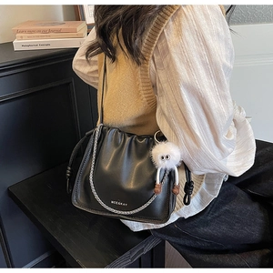 Detail of black pleated cloud bag with silver chain and white plush eyeball charm
