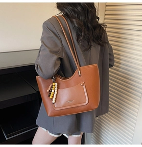 Detail of retro brown lychee leather tote bag with tricolor bead tassel and outer pocket