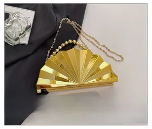 Detail showing shell-shaped evening clutch bag size compared to a smartphone