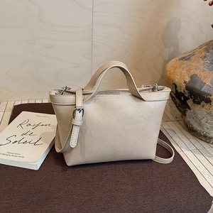 Detailed view of beige faux leather tote bag with adjustable strap and dual handles