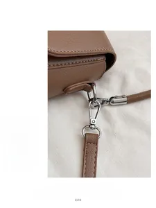 Dettaglio della pelle marrone con grana litchi e gancio in metallo argento della borsa