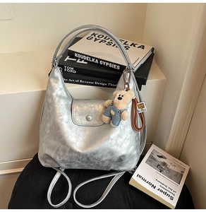 Detail of silver metallic textured backpack with a cute teddy bear charm on black chair